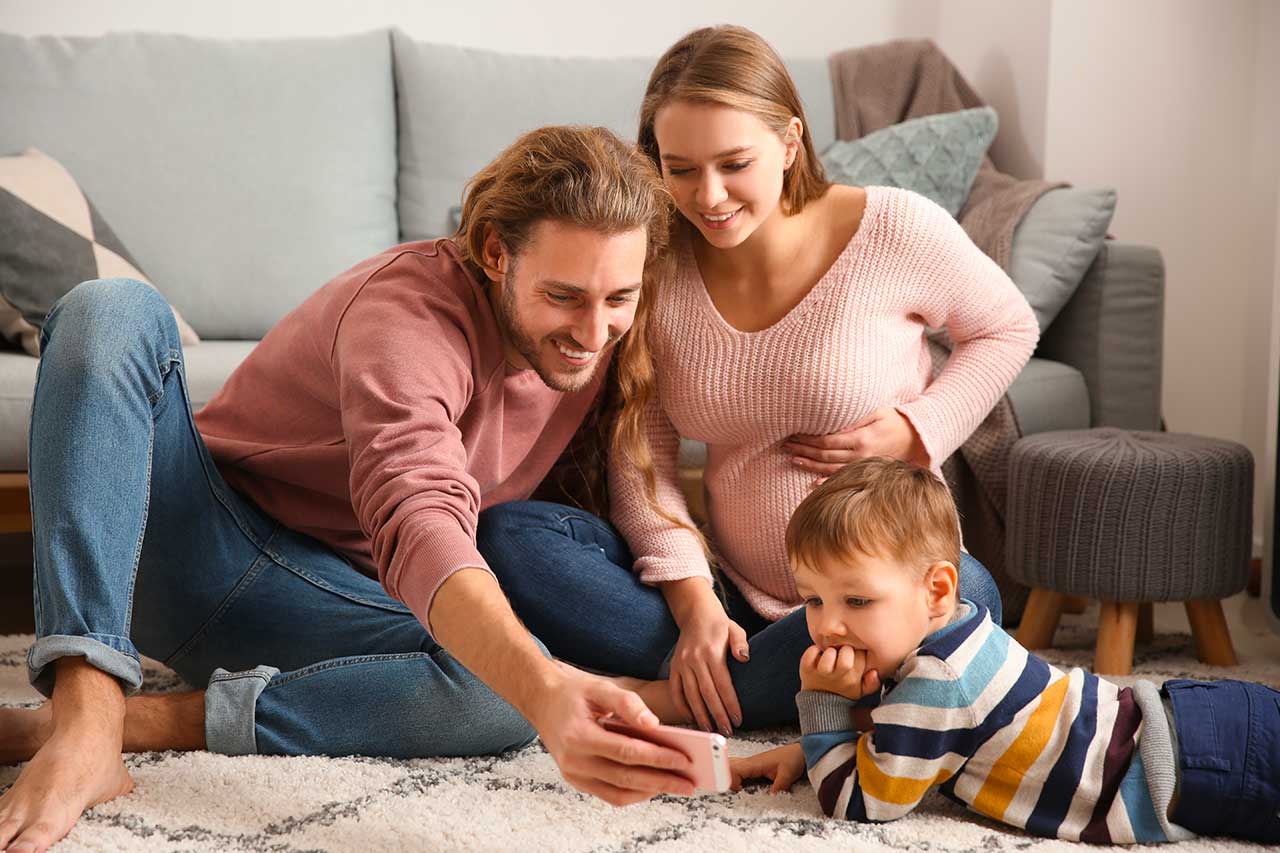 Photo de famille. La maman enceinte, le papa et leur petit garçon.